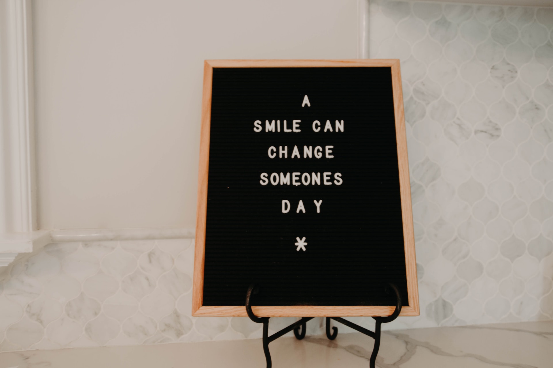 Little board with the words: A Smile Can Change Someone's Day that encourages others to be positive.